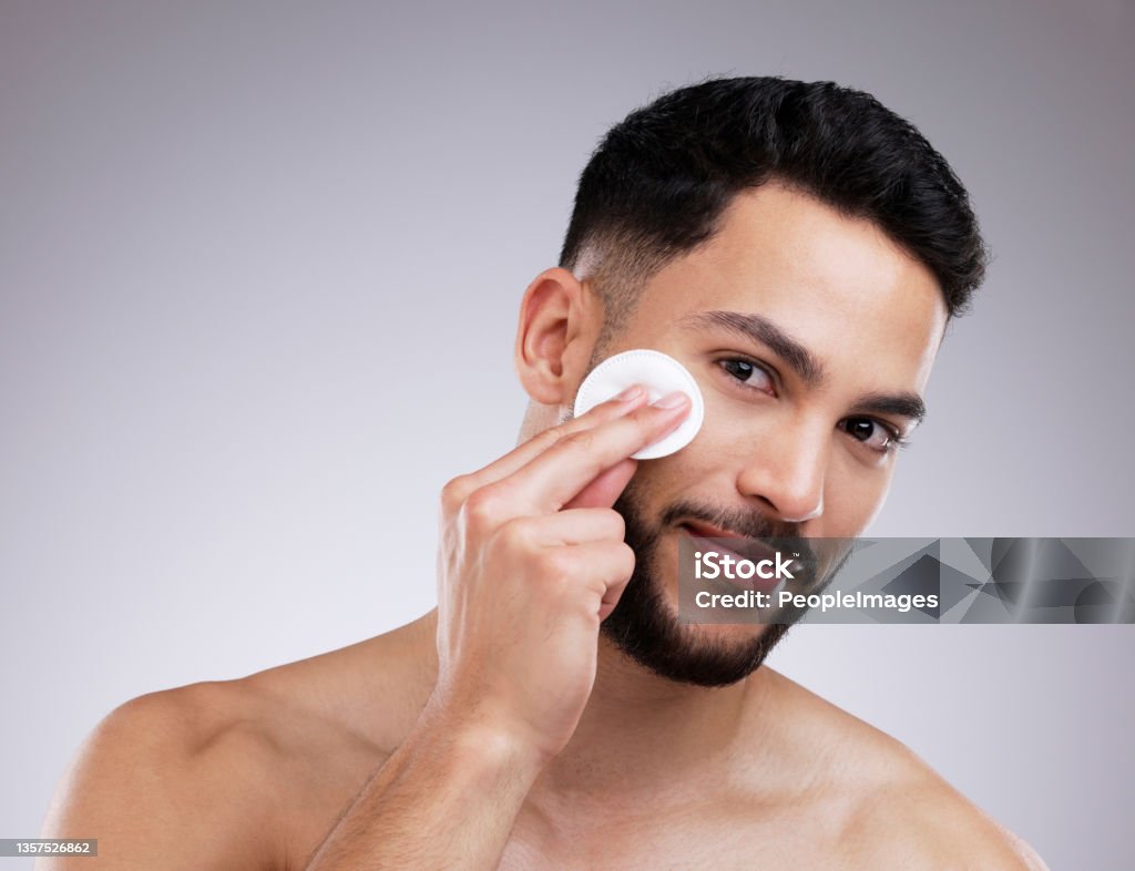 Shot of a young man applying product to his face using a cotton pad Toner helps to minimize pores Men Stock Photo