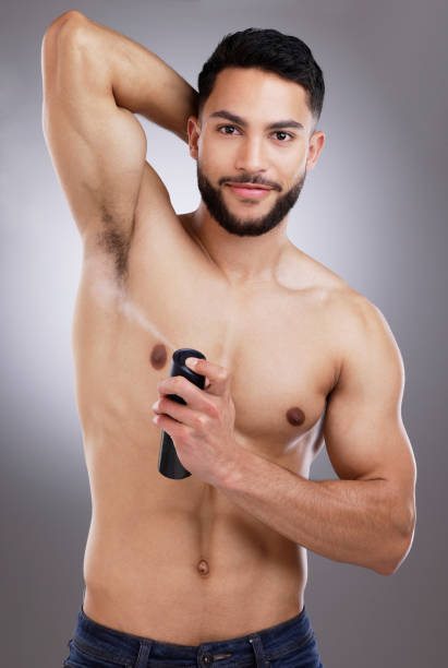 istock Shot of a man spraying deodorant into his armpits against a studio background 1357526871
