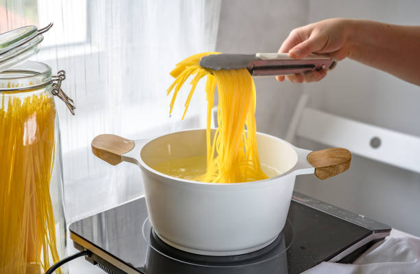 mano femenina sacando pasta caliente de la olla - diat fotografías e imágenes de stock