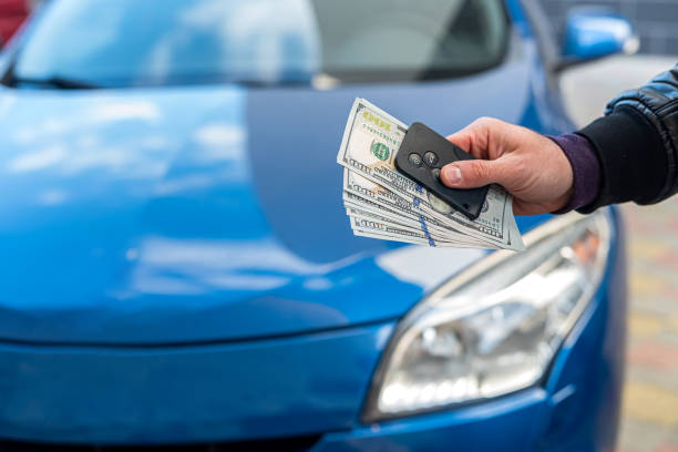 male hands in a business suit hold dollars and car keys on a background of blue cars male hands in a business suit holding dollars and car keys on a background of blue beautiful car. Business concept. The concept of buying a car. Business concept cash for cars stock pictures, royalty-free photos & images