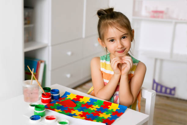 niña doblaba las manos en forma de corazón como signo de apoyo al autismo - autismo fotografías e imágenes de stock