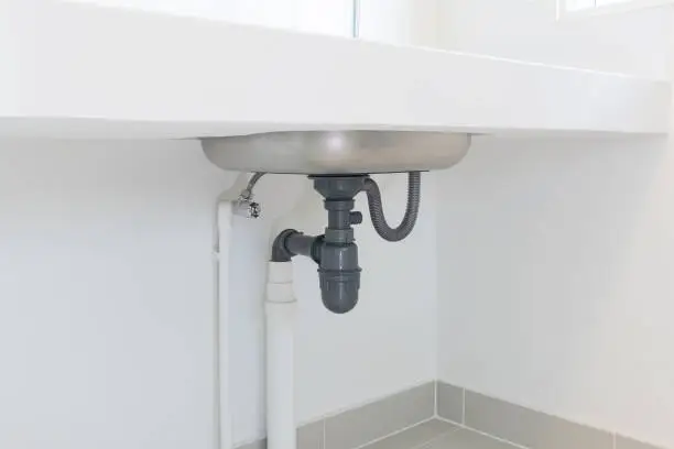 Photo of Drain pipe or sewer under kitchen sink for drain water and waste.