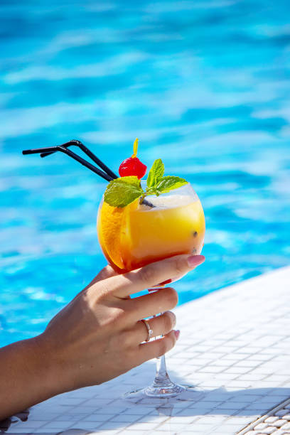 istock young woman is resting in the pool. Drinks a cocktail with a freshly squeezed orange. 1357530933