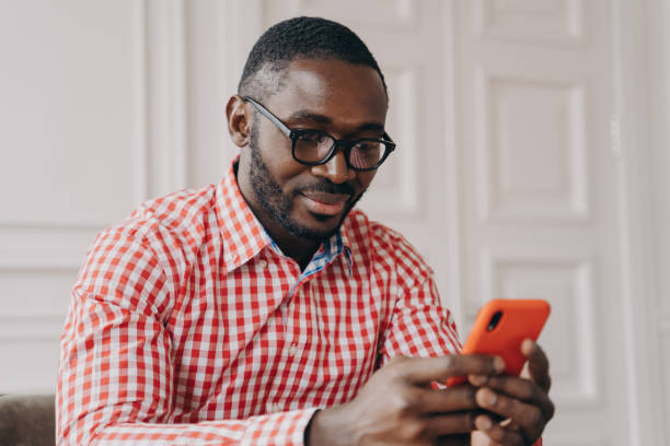 istock Cheerful millennial biracial man using smartphone, sitting at desk 1357531228