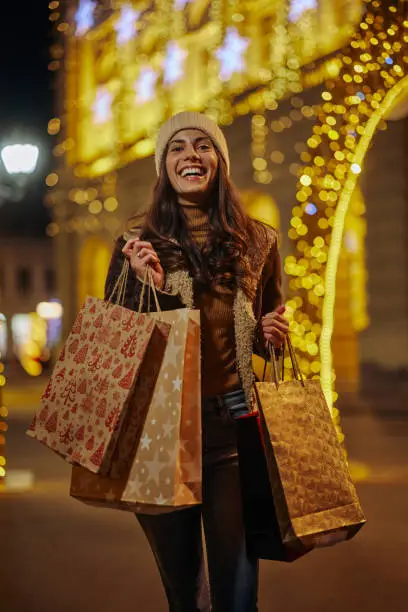 Woman enjoy in shopping, she walking through city and holding shopping bags with christmas gifts.