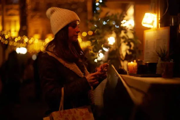 Young woman walking through the city streets at Christmas. She standing at the stand and buying some items