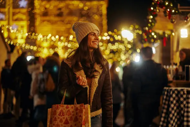 Young adult caucasian woman holding shopping bags, buying on Christmas market