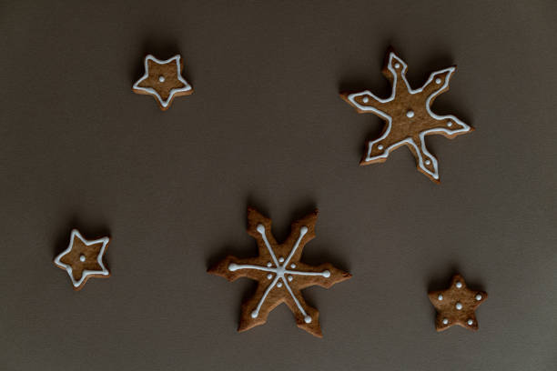 Four star gingerbread cookies and two snowflake gingerbread cookies on the brown table