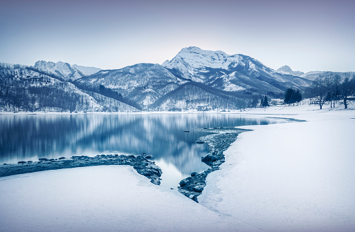 Gramolazzo lake and snow in Apuan mountains in winter after sunset. Garfagnana, Tuscany, Italy, Europe. Long exposure photography.