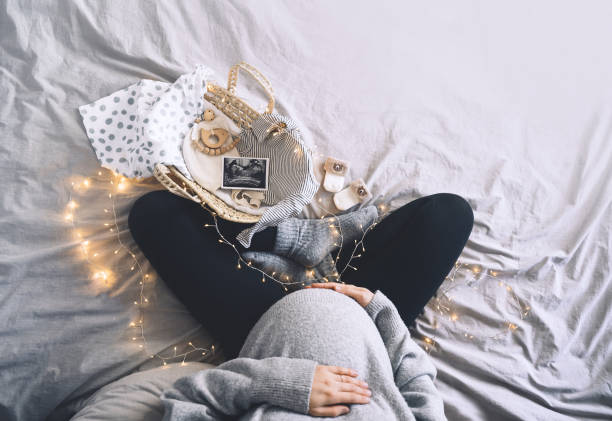 mujer embarazada con cesta de mimbre con ropa de recién nacido, imagen de ultrasonido, de regalo. futura madre esperando el nacimiento del bebé durante el embarazo. - party newborn baby hospital fotografías e imágenes de stock