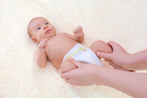 Mom gives a foot massage to a baby , topview Gymnastics for newborns