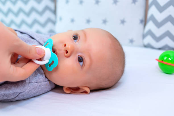 istock Mom's hand puts the pacifier in the baby's mouth 1357538411