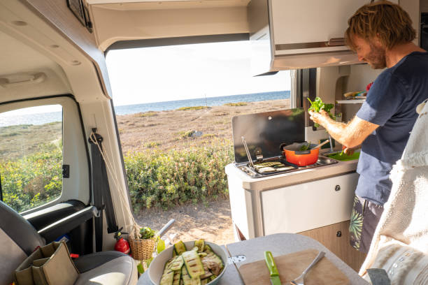 istock Man cooking in a camper-van, ocean view 1357538713