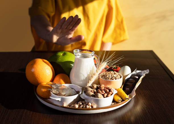 concepto de dieta de eliminación. una mujer evita los alérgenos alimentarios: pescado, mariscos, productos lácteos, cacahuetes, nueces de árbol, huevos, chocolate, trigo, soja, cítricos. - allergy food peanut pollen fotografías e imágenes de stock