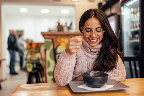 Smiling adult woman, with glasses, waiting for her food to cool. stock photo
