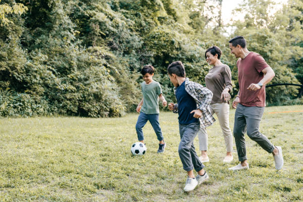 Family running in the park with soccer ball stock photo