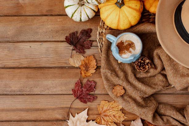 istock Autumn fall composition. Wooden desk table with warm sweater, hot coffee, hat and pumpkin. Flat lay, top view. Nordic, hygge, cozy home concept 1357541886