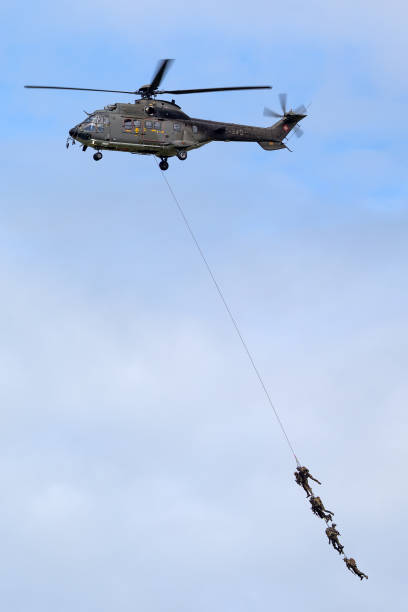 helicóptero utilitario militar aerospatiale as532 de la fuerza aérea suiza que transporta tropas por suspensión de cuerda. - as532 fotografías e imágenes de stock