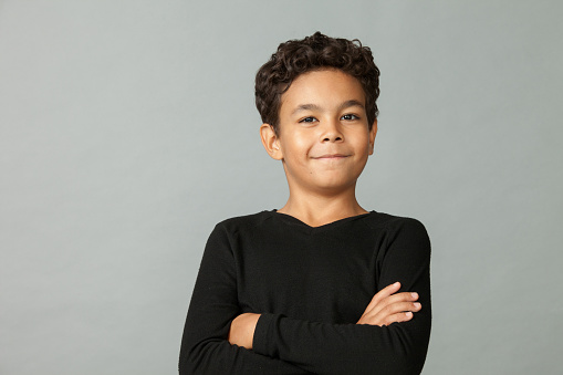 Close up studio portrait of 9 year old african american boy in black t-shirt on gray background