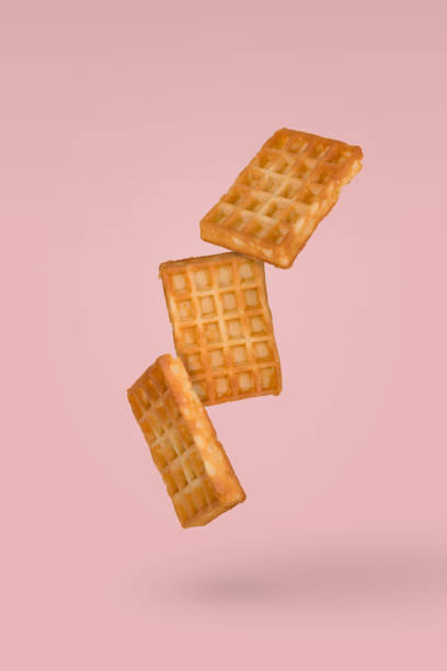 istock Soft waffles flying in air isolated on a pasel yellow background 1357544868