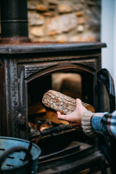 istock Young Woman Throws Wood in the Stove 1357546592