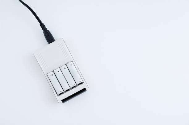 istock Four AA batteries are charged on  charger. White background. 1357547848