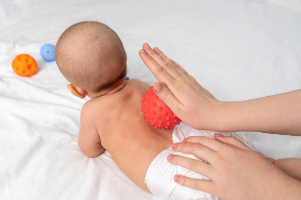 istock Doctor hands massage newborn with red rubber ball 1357547944