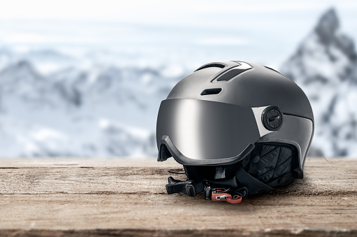 ski helmet with visor on mountains background. Modern grey ski helmet with sun visor on mountains background. winter sports helmet. Mountain Resort. copy space