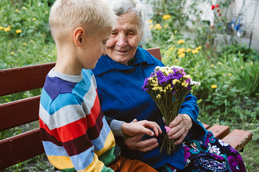 Reunited, family, togetherness, relationships, meeting, embracing. Grandson visit grandmother gives flowers after long break due to coronavirus quarantine .