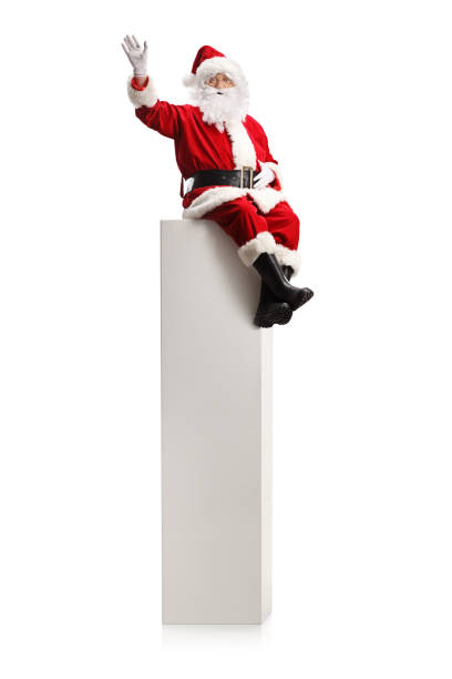 istock Santa claus sitting on a tall white column and waving 1357548196