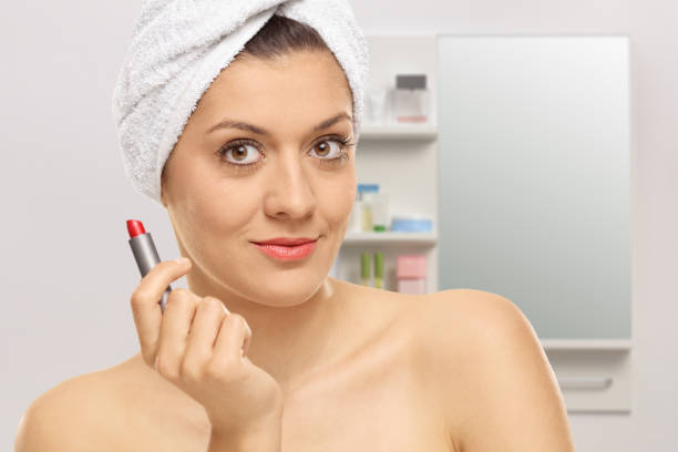 Young woman holding a red lipstick in a bathroom