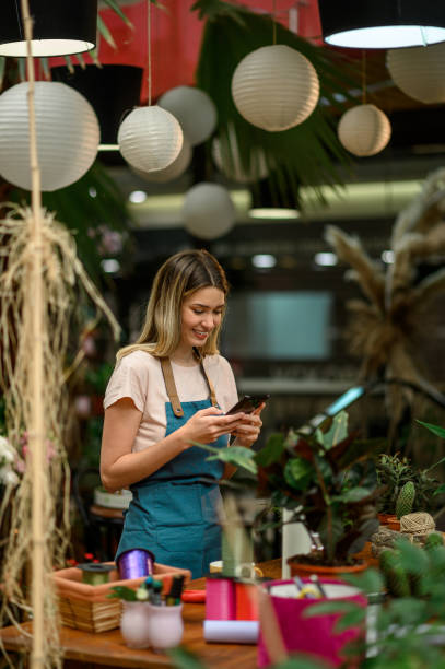 istock Florist using smartphone in a flower shop 1357548564