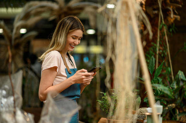 istock Florist using smartphone in a flower shop 1357548572