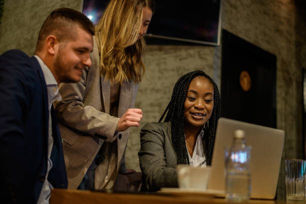 istock Cheerful work colleagues working on a laptop while having a meeting in a cafe 1357548581