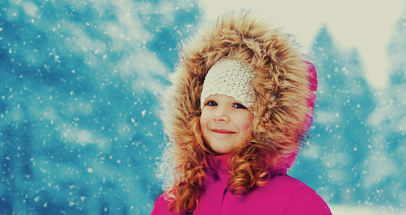 Winter portrait of happy smiling little girl child outdoors on snowy background