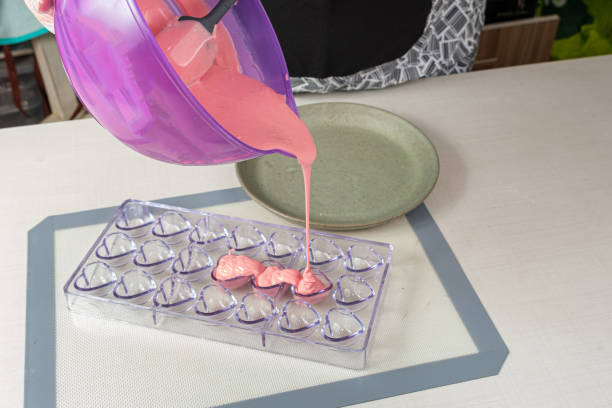 istock Confectionery pouring polycarbonate-shaped strawberry ganache. 1357549377