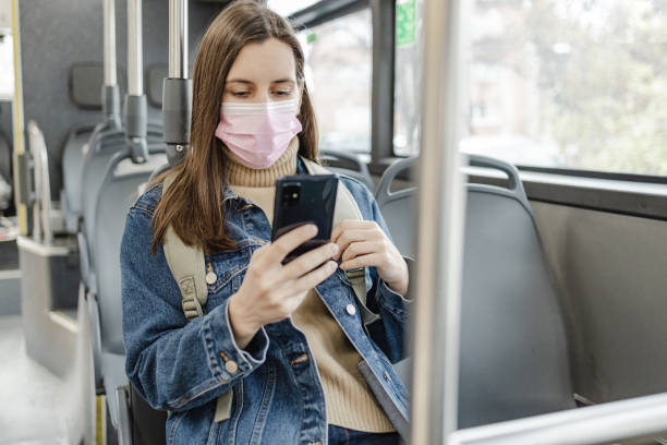 istock Woman with a protective face mask in a bus, using smart phone 1357550052