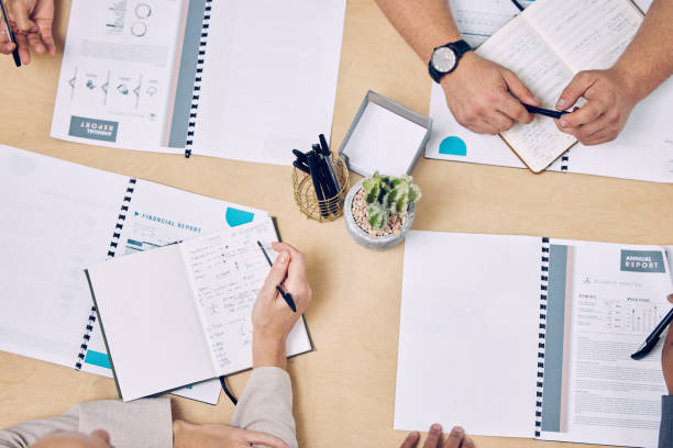 istock High angle shot of a group of unrecognizable businesspeople looking over paperwork while sitting around a table in the boardroom 1357550151