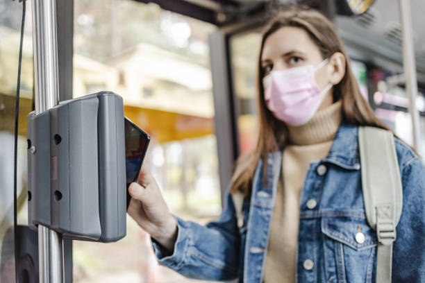 istock Woman with a protective face mask, paying a bus ticket with smart phone 1357550198