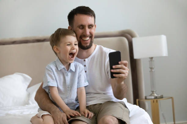 istock Excited laughing boy and dad using app on mobile phone 1357550413