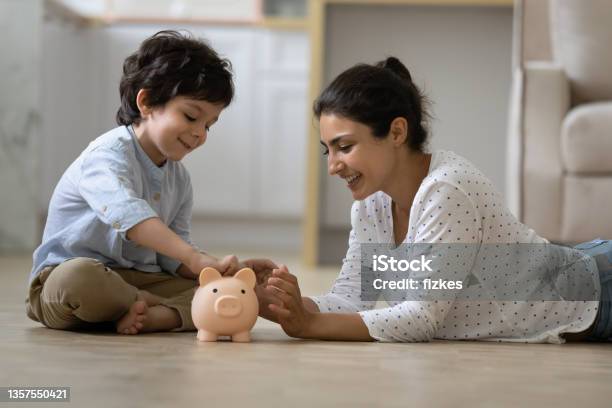 Happy Indian Kid And Young Mom Saving Money Together Stock Photo - Download Image Now