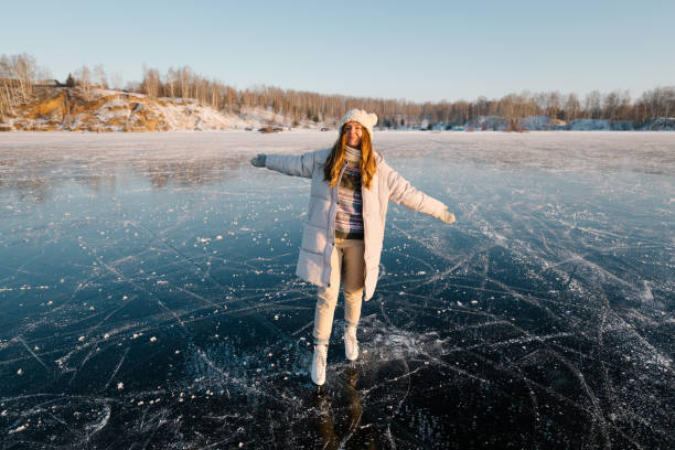 une jeune femme patine sur la glace d’un lac gelé. journée ensoleillée, ambiance d’activités hivernales ludiques. - ice winter white women photos et images de collection