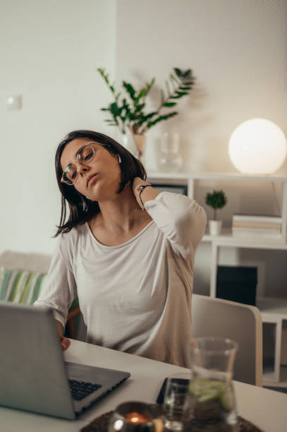 istock Beautiful woman having back and neck pain while using a laptop at home 1357551801
