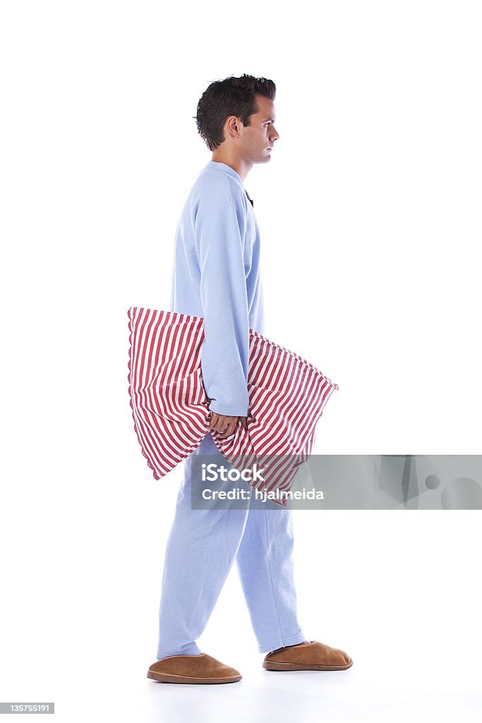 Man in blue pajamas carrying a red striped pillow Young man dress with nightclothes (isolated on white) Men Stock Photo