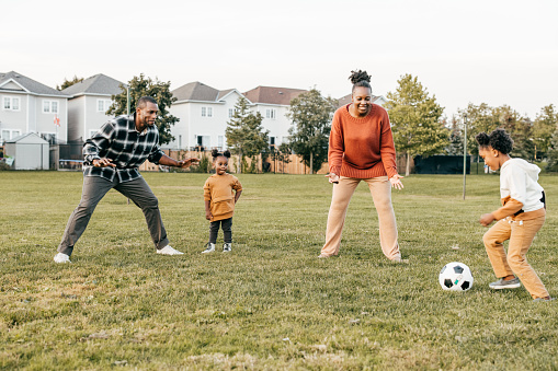 Family with two little  kids playing soccer outside
