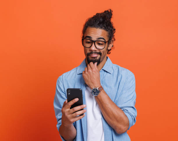 un jeune homme afro-américain choqué lisant de mauvaises nouvelles inattendues sur smartphone avec la bouche ouverte - 18602 photos et images de collection