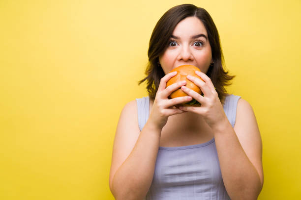 istock Hungry woman enjoying a burger 1357557153
