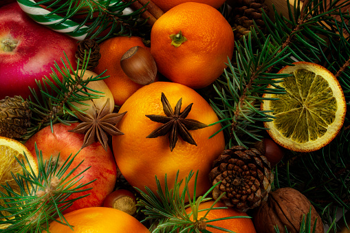 Christmas composition of fresh fruits, Christmas tree branches, dry oranges, cinnamon sticks and star anise, top view. Natural background.