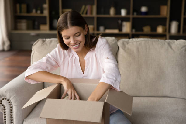 istock Happy young curious woman unpacking carton box. 1357564404