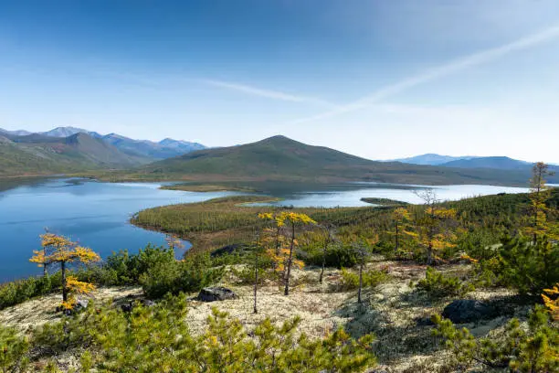 Russia. Magadan Region. A beautiful forest lake against the backdrop of the Big Anngachak mountain range. Autumn in the vicinity of Lake Jack London.